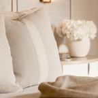 Close-up of beige cushions and blanket with a blurred background
