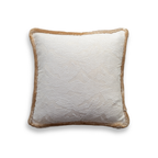 Product shot of a decorative cushion which features a white textured embroidered fabric with a tan velvet fringe trim around the edge of the cushion.