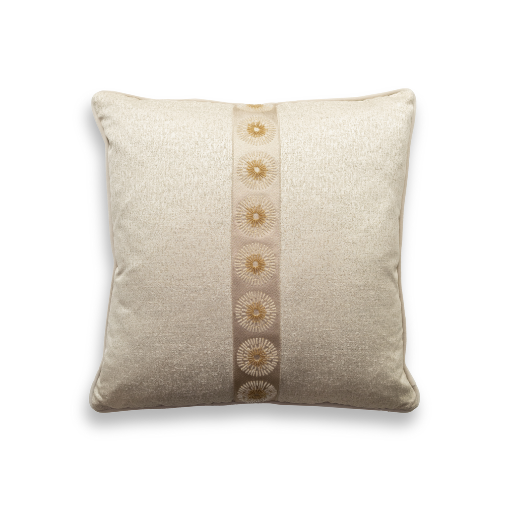 Product shot of the front of a decorative cushion which features a champagne textured fabric base, with an elegant statement trim down the centre which features intricate embroidered patterned.